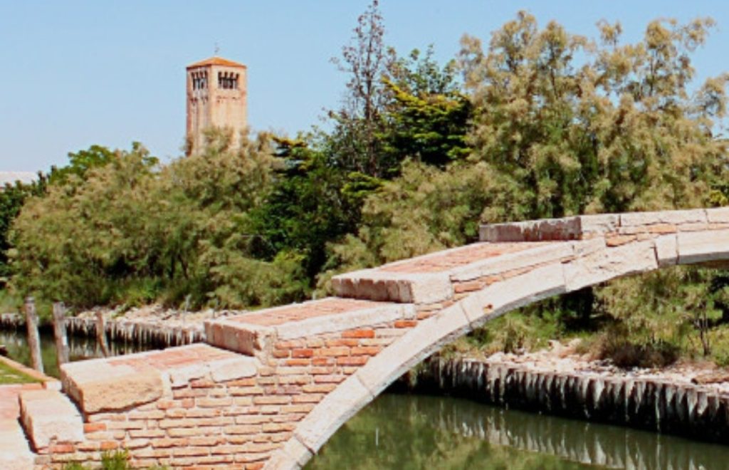 Ponte del Diavolo bridge crossing a quiet canal in Torcello island, Venice.